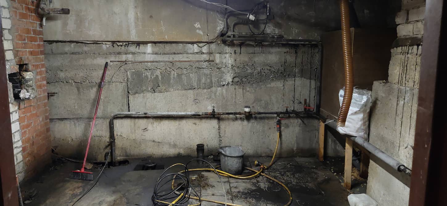 An image of a Basement renovation process. Dark dirty room with pipes.
