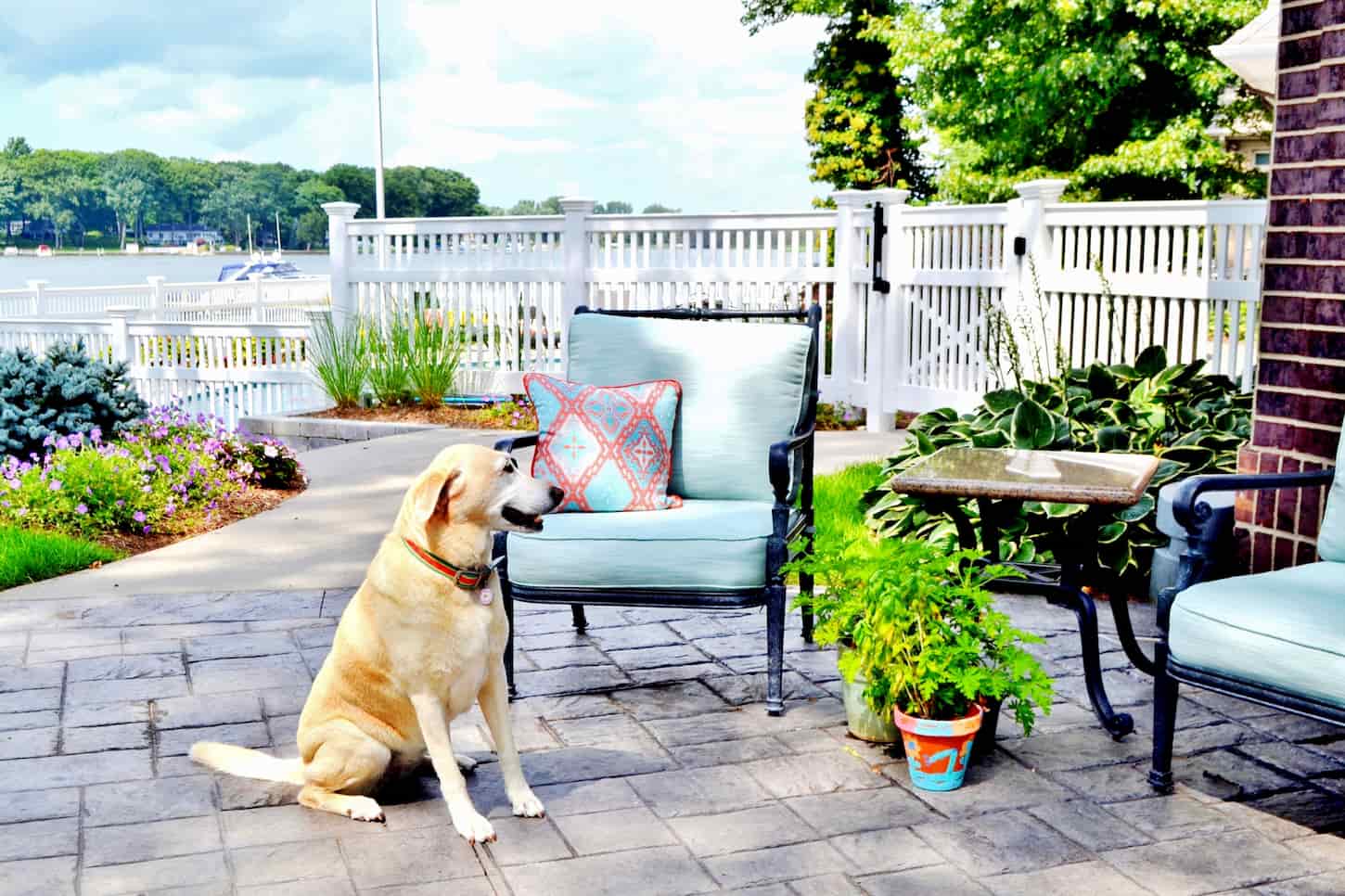 An image of an Outdoor patio space with a white fence and furniture.