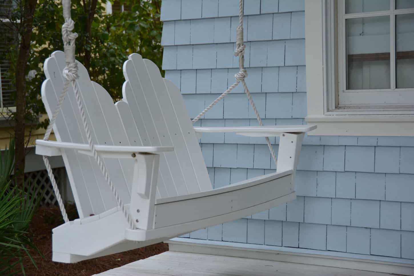 An image of a front porch-white swing.