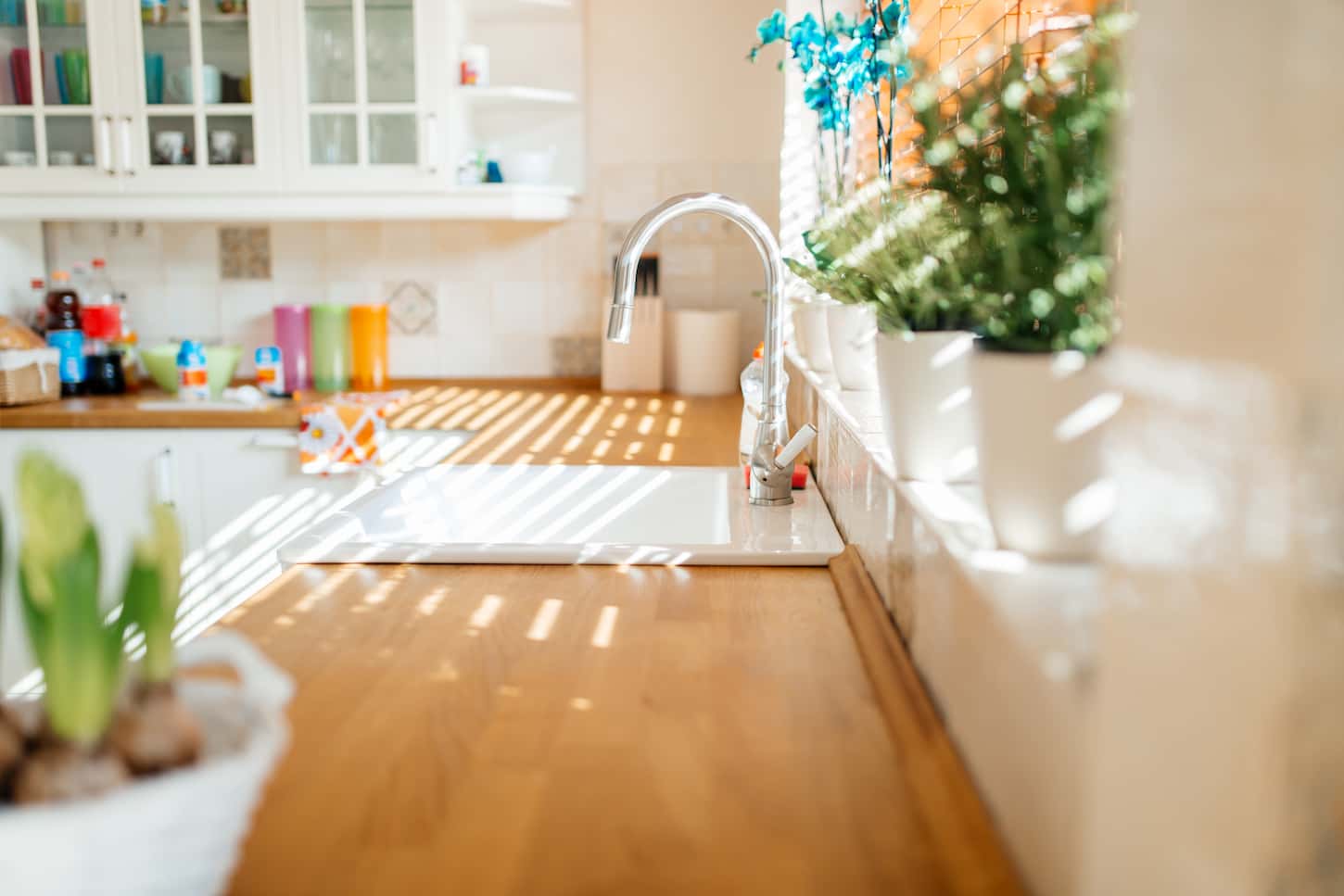 An image of a Modern white kitchen sink with morning sun rays.