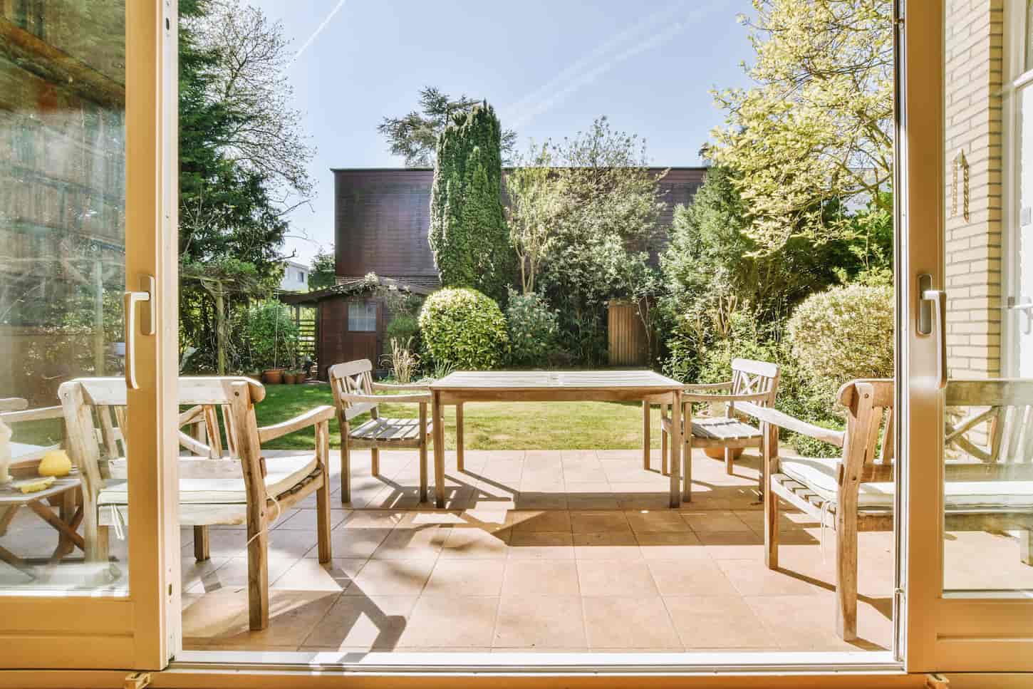An image of a Neat paved patio with sitting area and small garden near wooden fence.