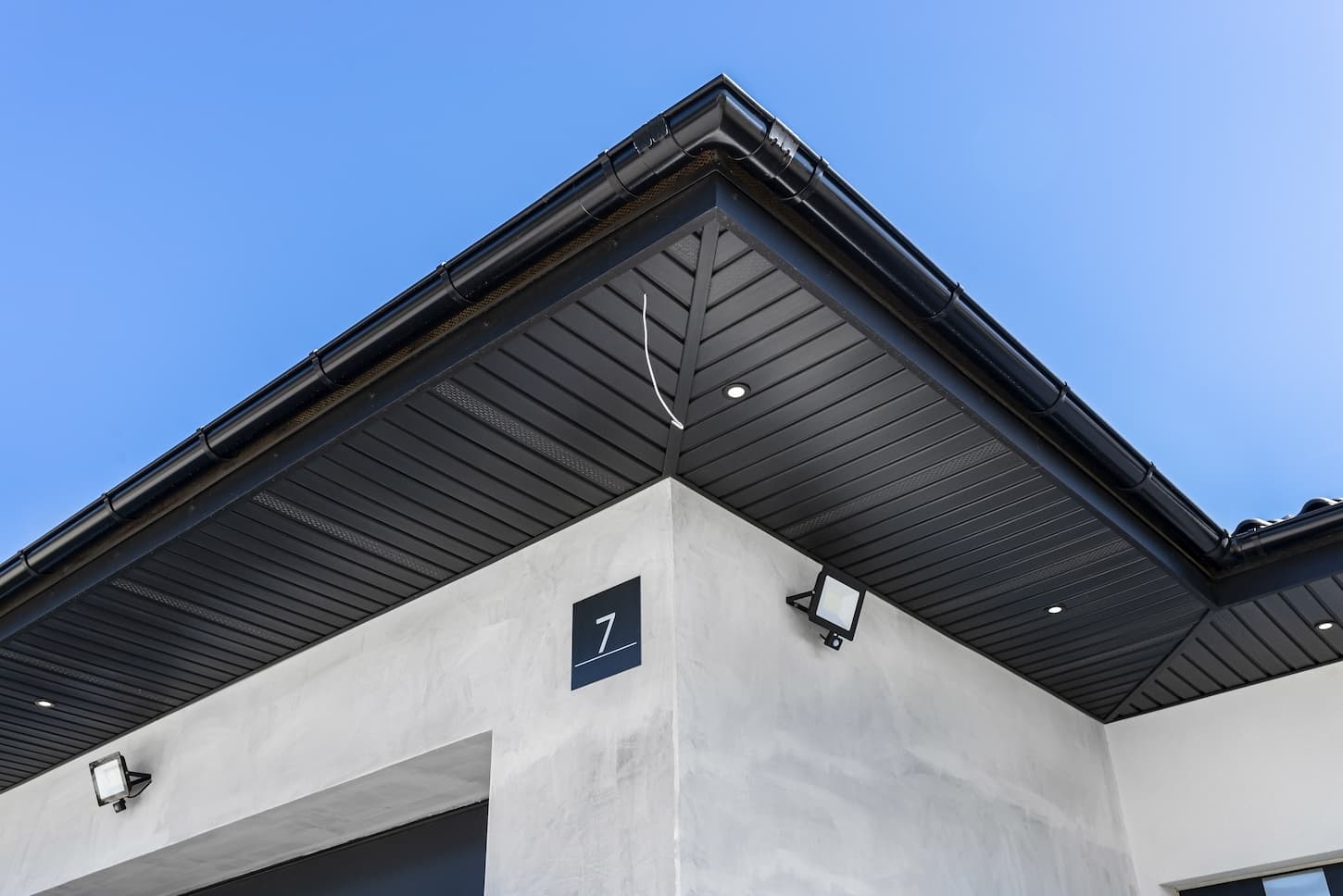 An image of A modern graphite herringbone roof lining is attached to the trusses, visible turned on LED lights.