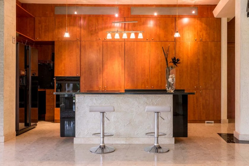 An image of a Modern kitchen area surrounded by wooden built-in cabinets and a marble kitchen island.