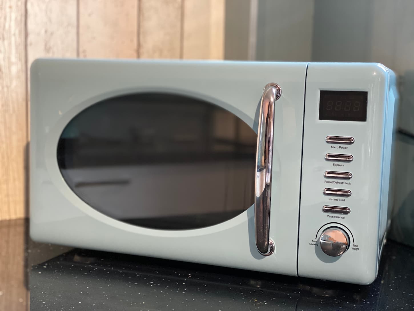 An image of a Blue Microwave oven on a kitchen glitter work top.