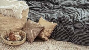 An image of Decorative items in a cozy home interior. Wicker straw large bag, and decorative elements. Concepts of style and comfort.