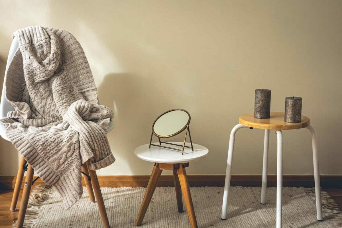 An image of a minimalist home interior, decor details, a mirror, candles, and a knitted element.